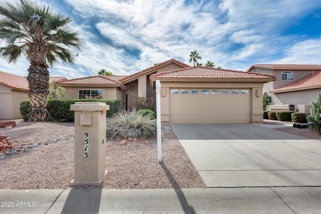 view of front of property featuring concrete driveway, an attached garage, a tiled roof, and stucco siding