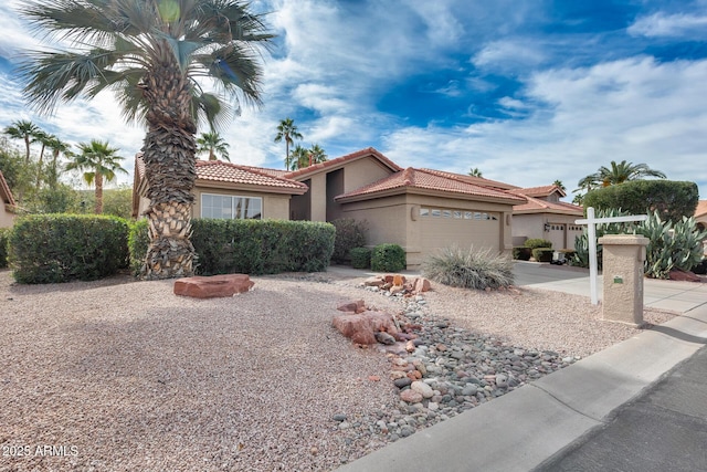 view of front facade featuring driveway, an attached garage, a tiled roof, and stucco siding