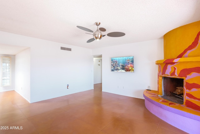 unfurnished living room with a fireplace with raised hearth, a textured ceiling, visible vents, and a ceiling fan