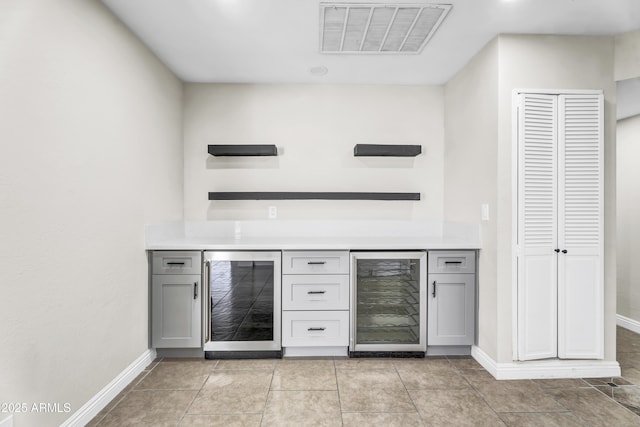 bar featuring a bar, beverage cooler, visible vents, and baseboards