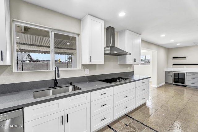 kitchen featuring white cabinets, dark countertops, wall chimney exhaust hood, black electric cooktop, and a sink