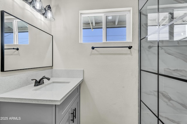 full bathroom featuring a textured wall, vanity, and a marble finish shower