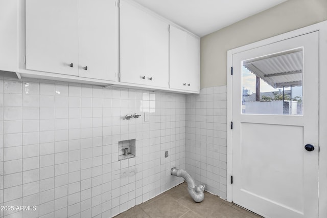 laundry room featuring light tile patterned floors, hookup for an electric dryer, washer hookup, tile walls, and cabinet space