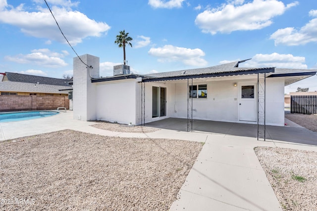 back of property with central AC, a patio, fence, and a fenced in pool
