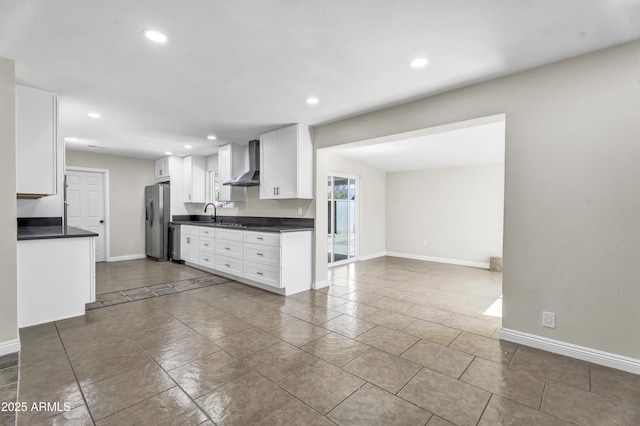 kitchen with white cabinets, dark countertops, wall chimney exhaust hood, appliances with stainless steel finishes, and recessed lighting