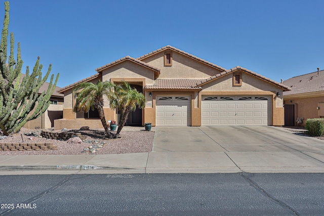 view of front of property with driveway, a tiled roof, an attached garage, and stucco siding