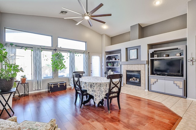 dining room featuring a fireplace, wood finished floors, a ceiling fan, visible vents, and built in features