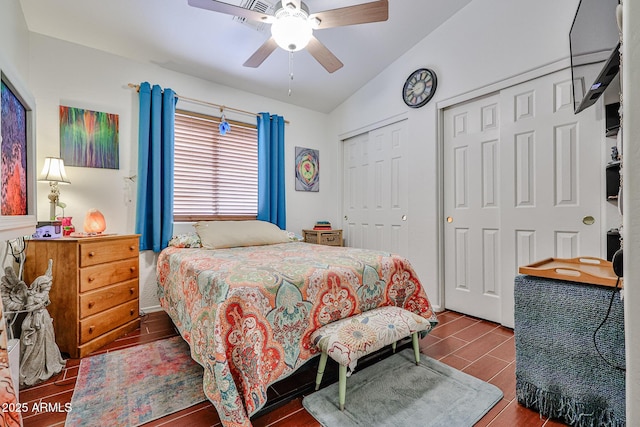 bedroom featuring vaulted ceiling, two closets, a ceiling fan, and wood tiled floor