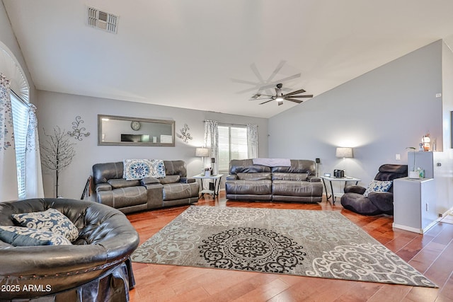 living area featuring a ceiling fan, lofted ceiling, visible vents, and wood finished floors