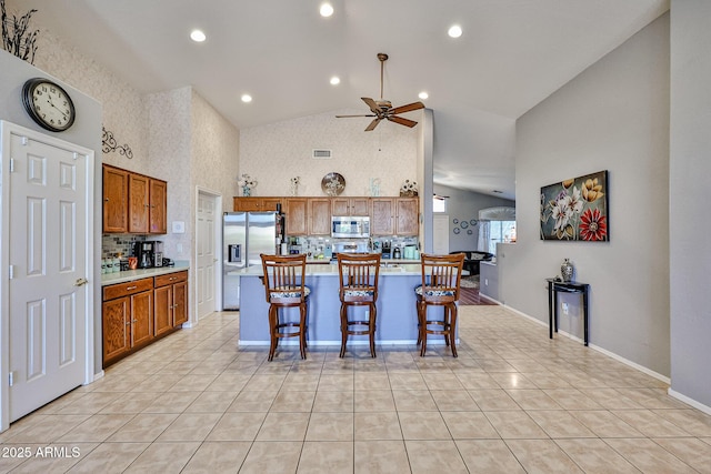 kitchen featuring light countertops, appliances with stainless steel finishes, brown cabinetry, and light tile patterned flooring