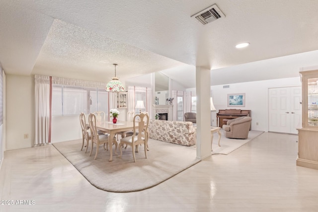 dining space featuring a healthy amount of sunlight, light hardwood / wood-style floors, and a textured ceiling