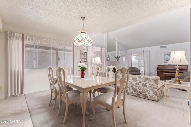 dining area with vaulted ceiling, carpet, a fireplace, and a textured ceiling