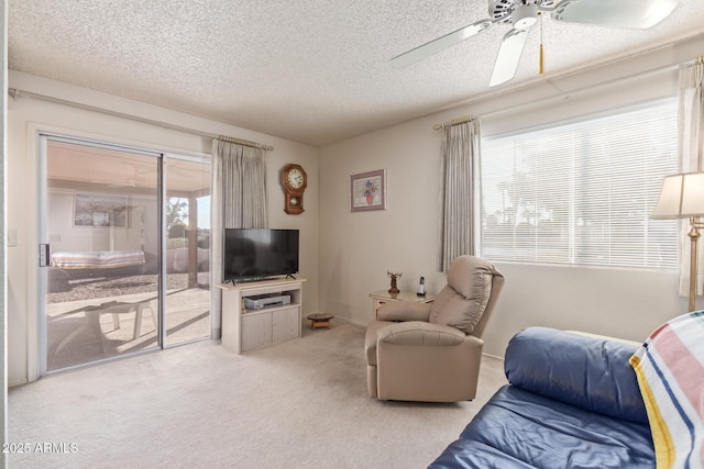 carpeted living room featuring ceiling fan and a textured ceiling