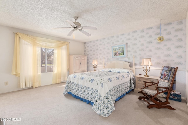 bedroom featuring ceiling fan, light colored carpet, and a textured ceiling