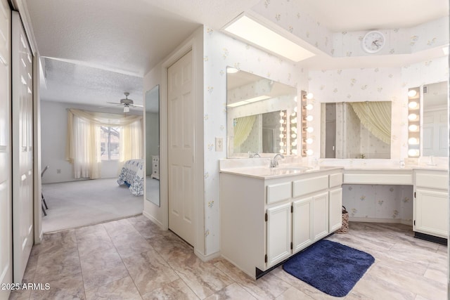 bathroom featuring ceiling fan, vanity, and a textured ceiling