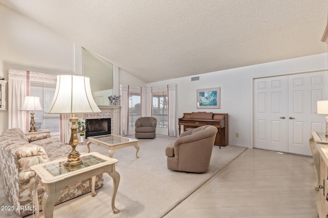 living room with light hardwood / wood-style floors, vaulted ceiling, and a textured ceiling