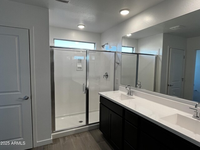 bathroom with a stall shower, a sink, and wood tiled floor