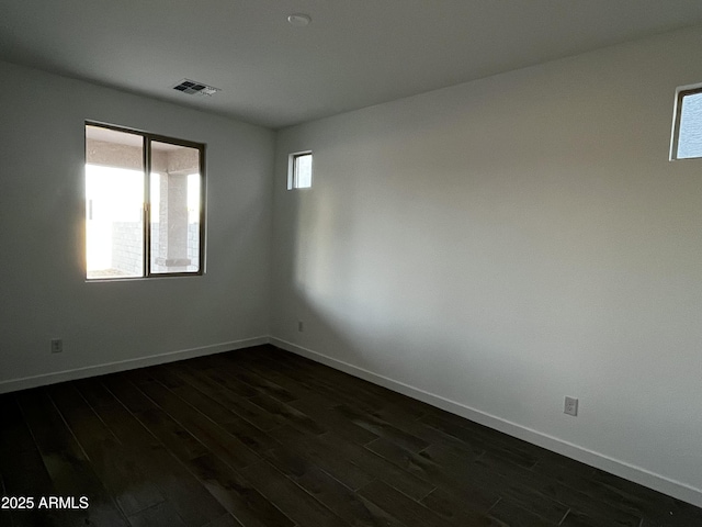 spare room featuring baseboards, visible vents, and dark wood-style flooring