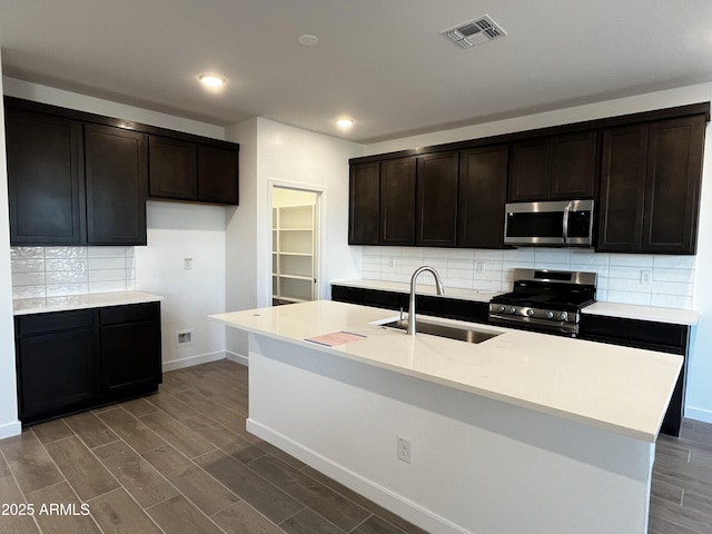 kitchen with stainless steel appliances, dark wood-style flooring, a sink, visible vents, and light countertops