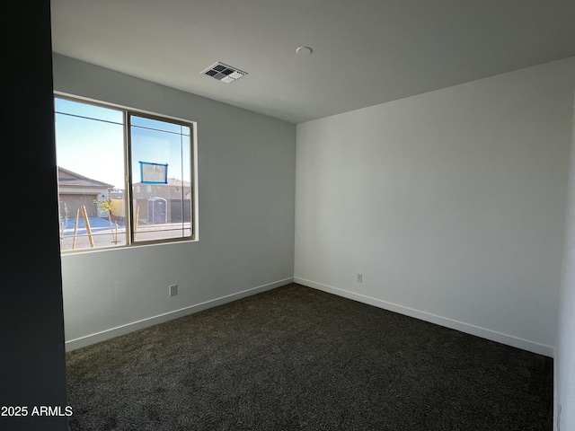 unfurnished room featuring visible vents, dark carpet, and baseboards