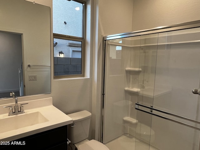 bathroom featuring toilet, a shower stall, and vanity