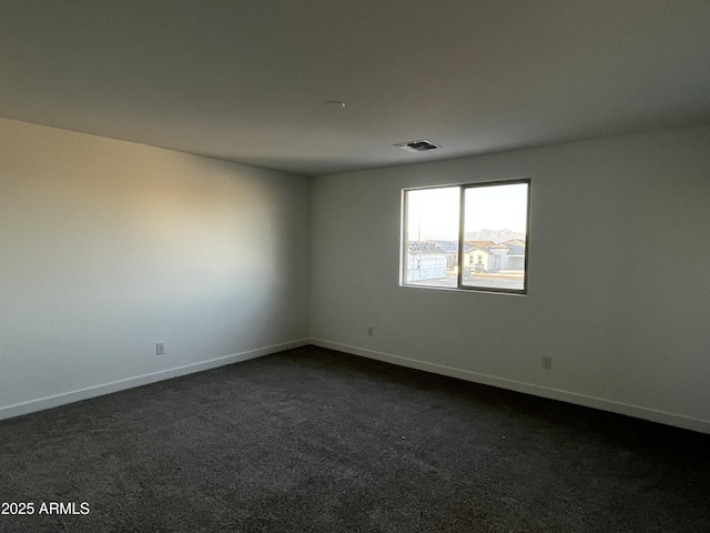 unfurnished room featuring dark carpet, visible vents, and baseboards