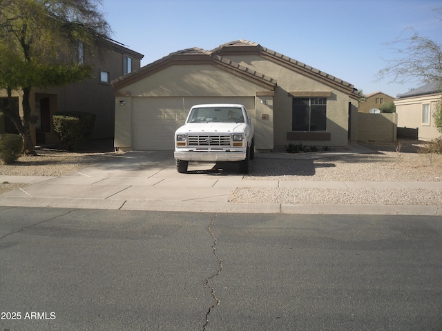 view of front of home featuring a garage, a tile roof, concrete driveway, and stucco siding