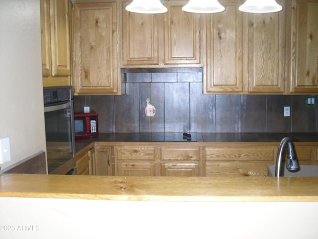 kitchen featuring oven, black electric cooktop, a sink, light brown cabinetry, and tasteful backsplash