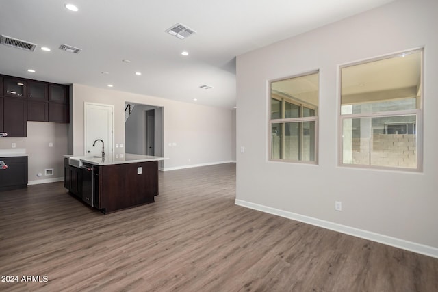 kitchen featuring dark brown cabinets, a kitchen island with sink, dark wood-type flooring, and sink