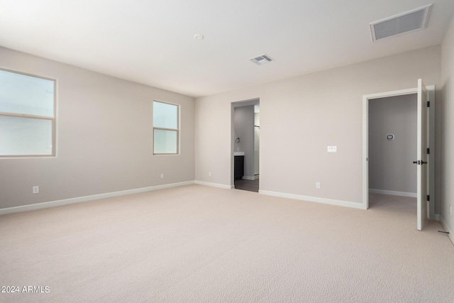 unfurnished bedroom with light carpet and connected bathroom