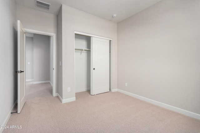 unfurnished bedroom featuring light colored carpet and a closet