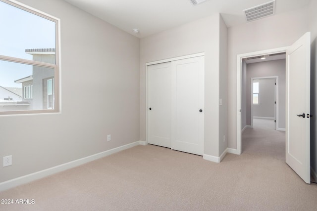 unfurnished bedroom featuring a closet and light colored carpet