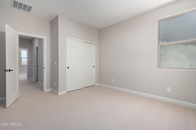 unfurnished bedroom with light carpet and a closet