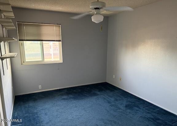 unfurnished room featuring a ceiling fan, dark carpet, and a textured ceiling