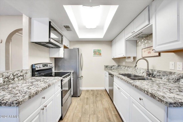 kitchen featuring white cabinets, a raised ceiling, stainless steel appliances, light wood-type flooring, and sink