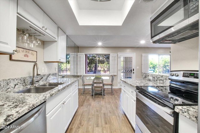 kitchen with light stone counters, light hardwood / wood-style floors, sink, white cabinetry, and stainless steel appliances