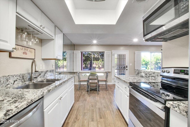 7502 E Carefree Dr Unit 106, Carefree, AZ 85377 - kitchen featuring a sink, light stone counters, white cabinetry, stainless steel appliances, and light wood finished floors