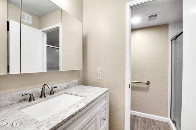 bathroom featuring wood-type flooring, an enclosed shower, and vanity