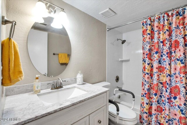 full bathroom featuring shower / bath combination with curtain, vanity, toilet, and a textured ceiling