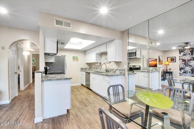 7502 E Carefree Dr Unit 106, Carefree, AZ 85377 - kitchen with visible vents, arched walkways, stainless steel appliances, white cabinetry, and light wood-type flooring