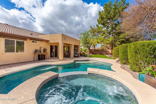 view of pool featuring a patio, fence, and a pool with connected hot tub