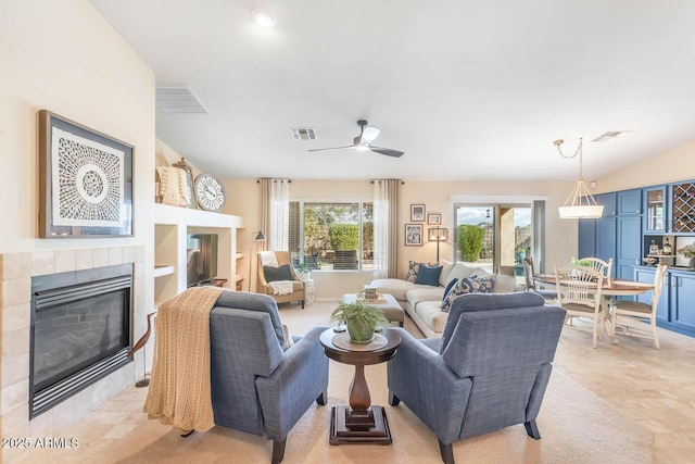 living area featuring vaulted ceiling, ceiling fan, a fireplace, and visible vents