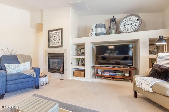 carpeted living area featuring built in shelves, visible vents, and a tile fireplace