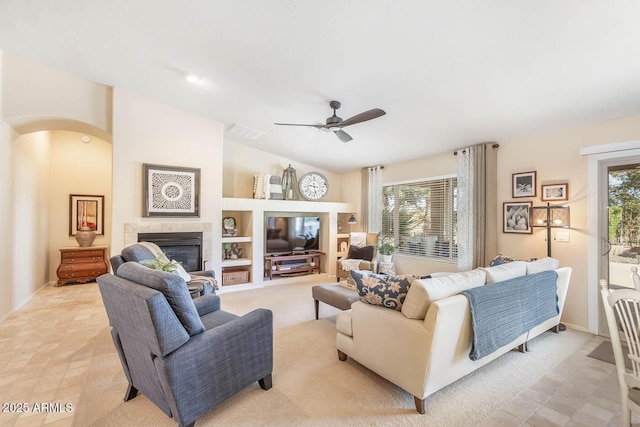 living room featuring a tile fireplace, vaulted ceiling, visible vents, and plenty of natural light