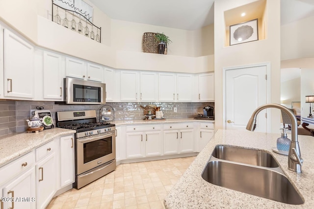 kitchen with white cabinetry, appliances with stainless steel finishes, decorative backsplash, and a sink