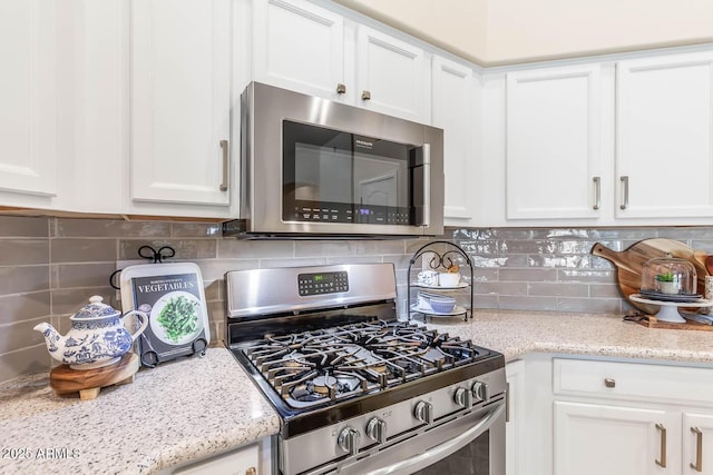 kitchen with stainless steel appliances, white cabinetry, and decorative backsplash