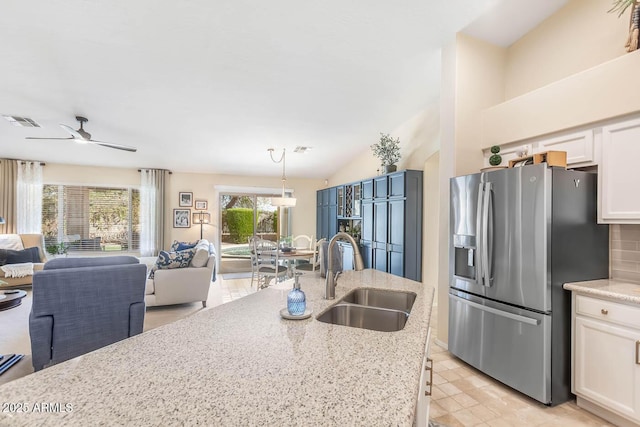 kitchen featuring visible vents, open floor plan, white cabinetry, a sink, and stainless steel fridge