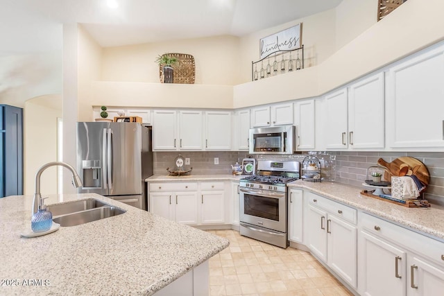 kitchen with a high ceiling, appliances with stainless steel finishes, decorative backsplash, and a sink