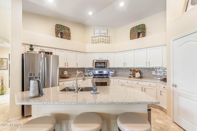 kitchen with appliances with stainless steel finishes, a sink, a breakfast bar, and tasteful backsplash