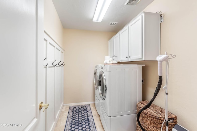 laundry area with cabinet space, light tile patterned floors, baseboards, visible vents, and washer and clothes dryer